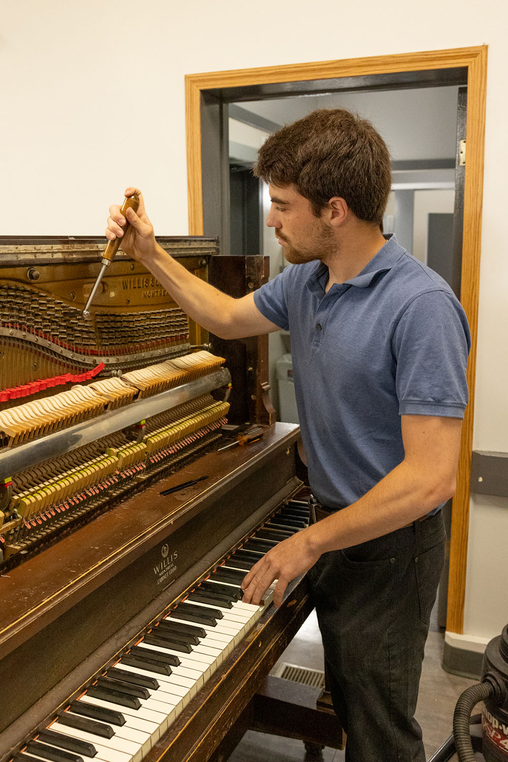 A young man tuning a piano